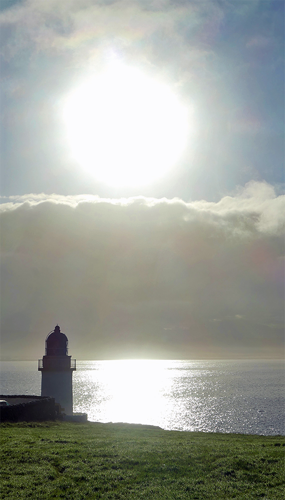 Picture of a low morning sun over a small lighthouse