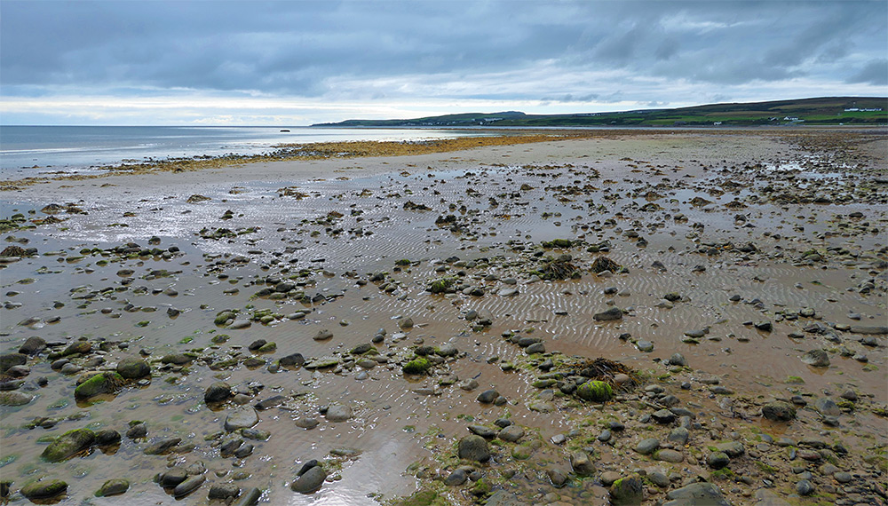 Picture of a beach at a sea loch, sandy with a variety of stones