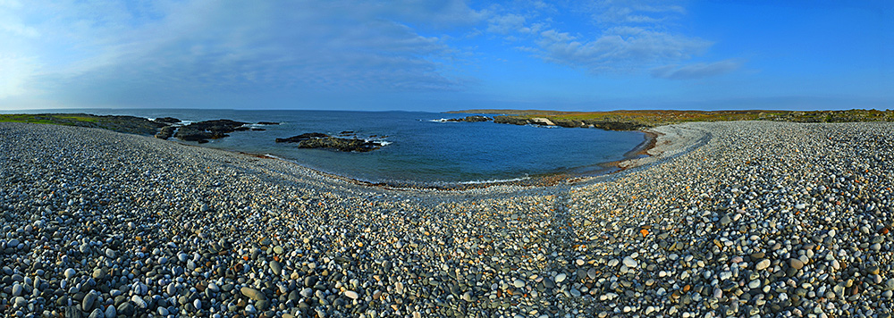Panoramic picture of a pebble beach in the September late afternoon sunshine