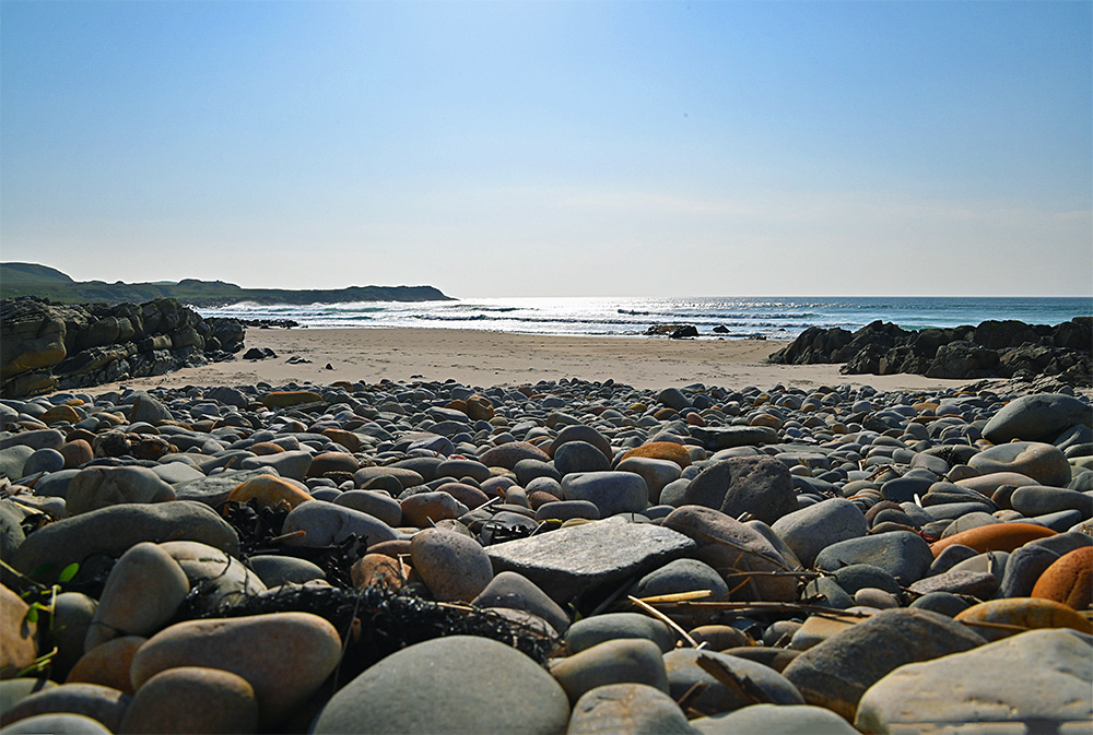Picture of a pebble beach merging into a sandy beach in a wide bay
