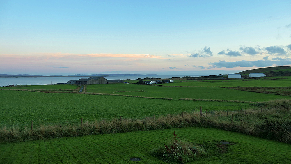 Picture of a coastal landscape along a sea loch with some distillery warehouses in the gloaming after sunset