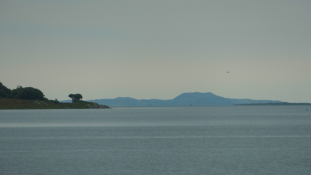 Picture of a view out of a sea loch on an overcast evening, an island in the distance