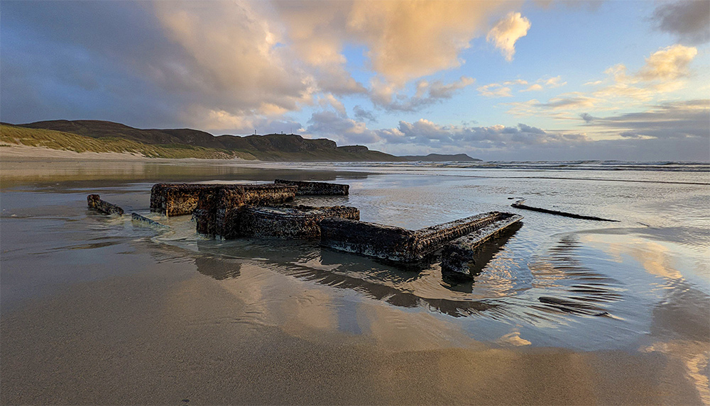 Picture of a wreck on a sandy beach in some mild evening light