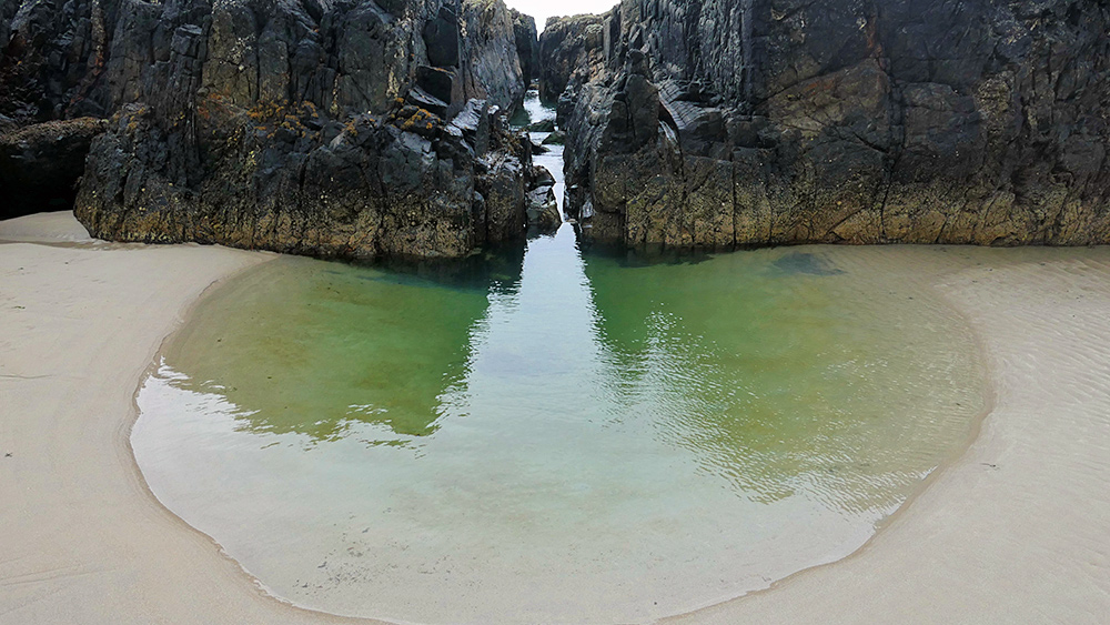 Picture of a rock channel and water pool at the end of a beach