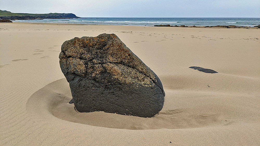 Picture of a large rock in the sand on a beach