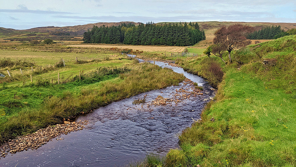 Picture of a small river flowing on a bend through a hilly landscape