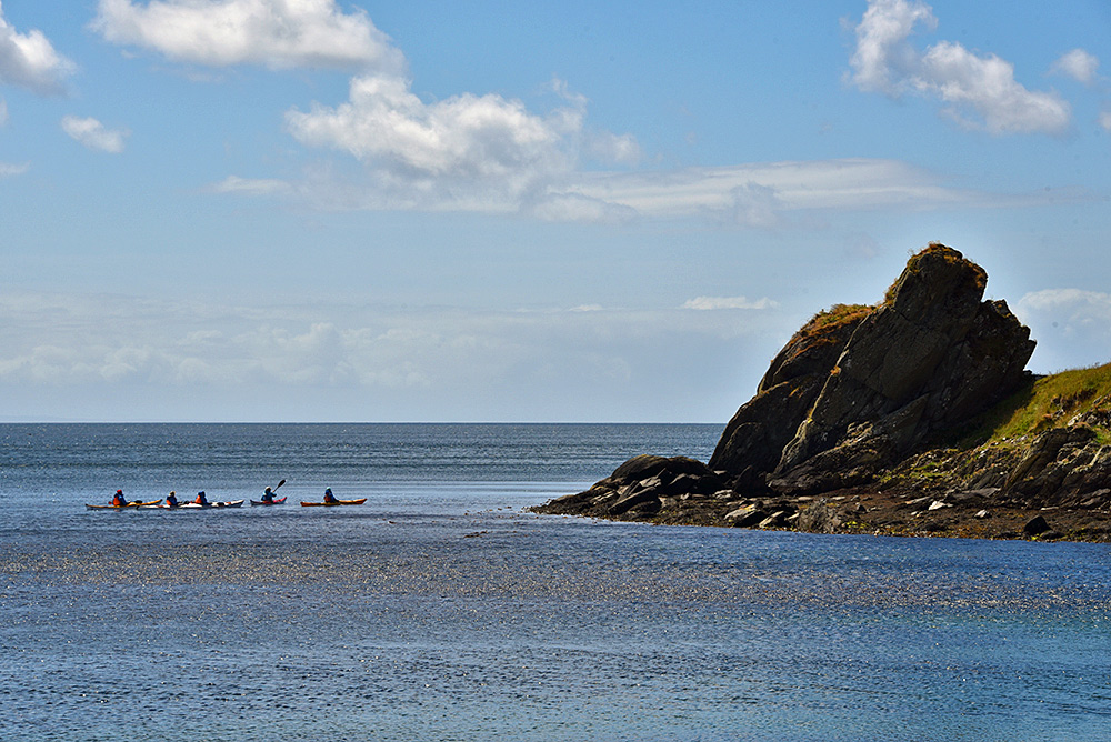 Picture of a group of kayakers near a distinctive coastal rock formation