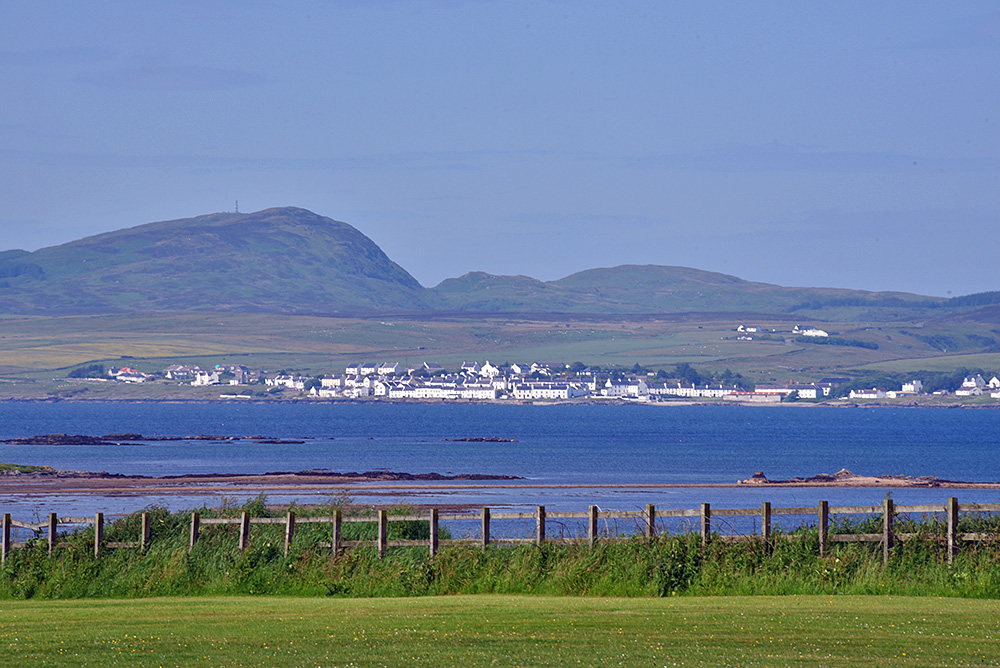 Picture of a coastal village seen across a sea loch from some playing fields