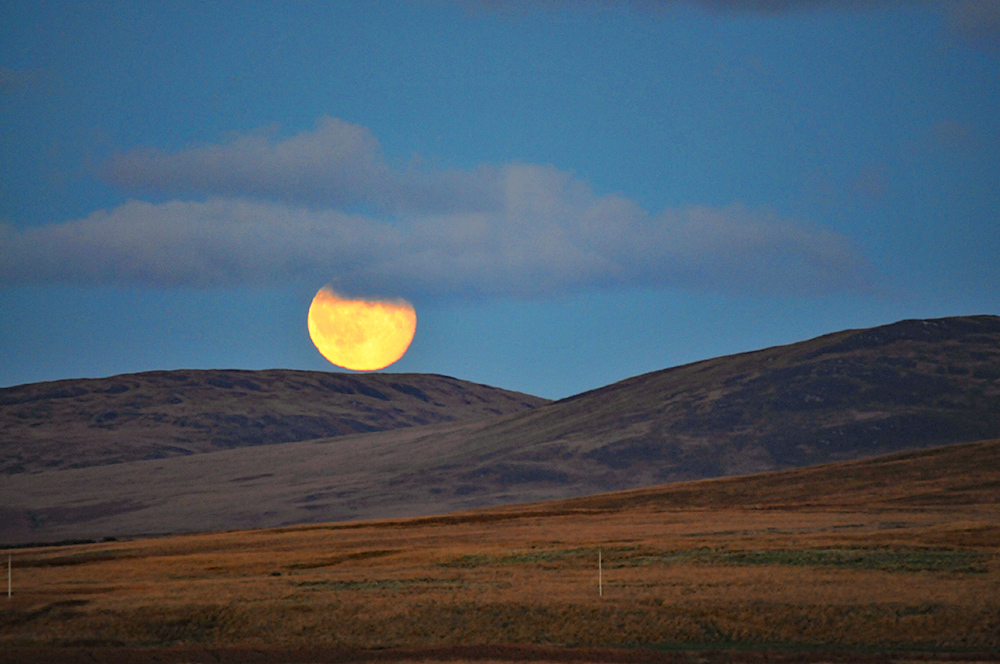 Picture of the Moon rising over some low hills on an October evening