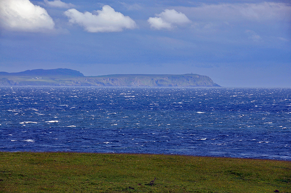 Picture of the mull of a peninsula seen across a sea loch on a windy day with lots of white horses on the water