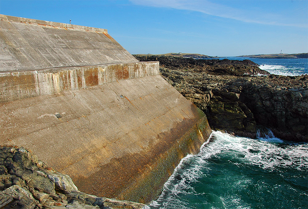 Picture of a bare concrete wall of a wave power station in some cliffs at the coast