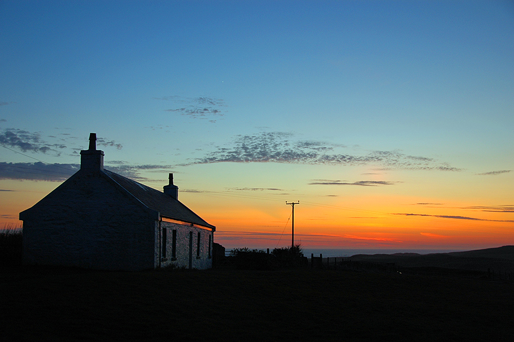 Picture of a cottage high above the sea in the last light of the gloaming