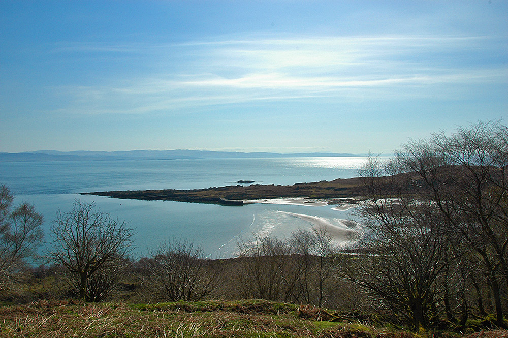 Picture of a small bay with a small old stone jetty, seen from a hillside above on a sunny April day