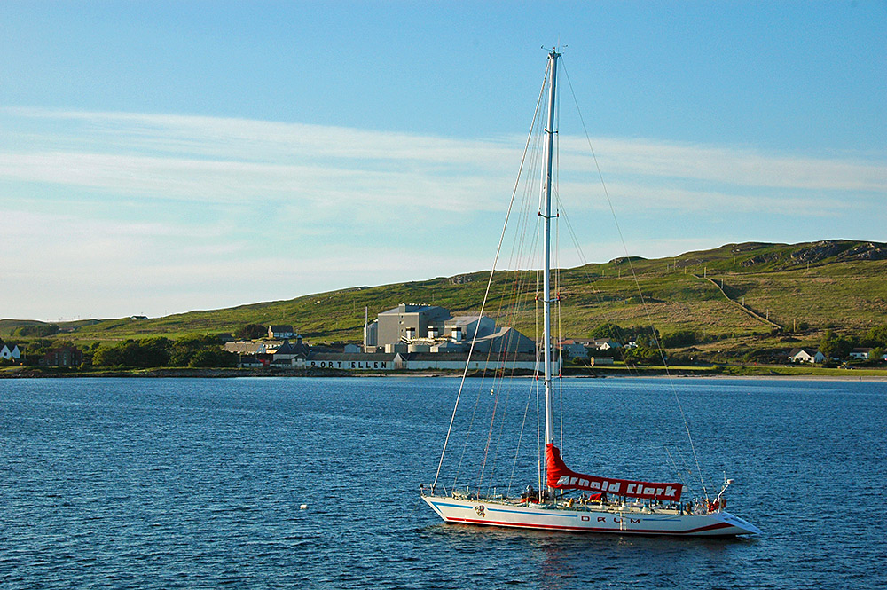 Picture of a large sailing yacht anchored off an old distillery and modern maltings