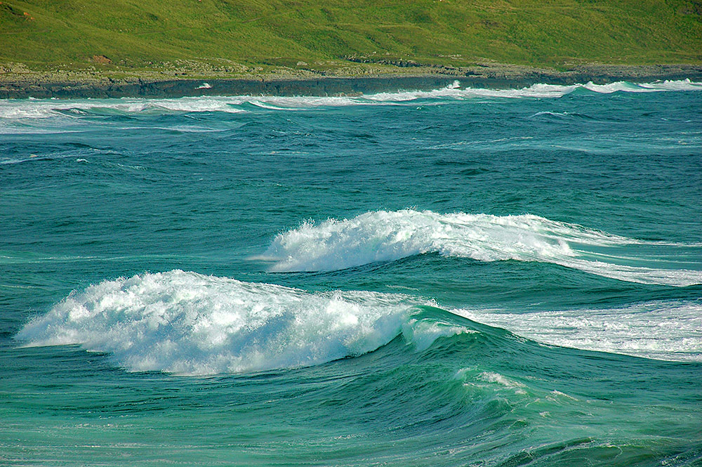 Picture of some big waves breaking as they approach a shore in a bay