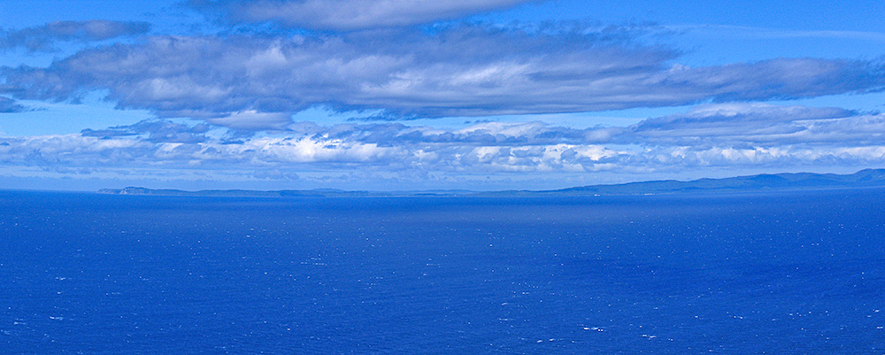 Panoramic picture of an island seen across the sea from a high cliff