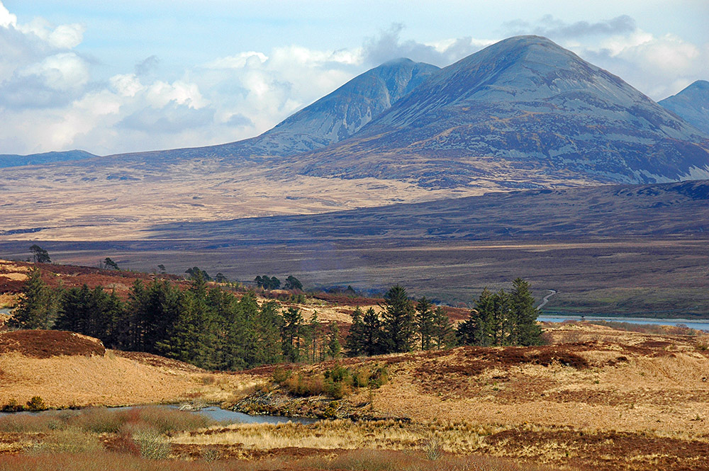 Picture of two large mountains towering over a landscape with a sound between two islands and a small loch