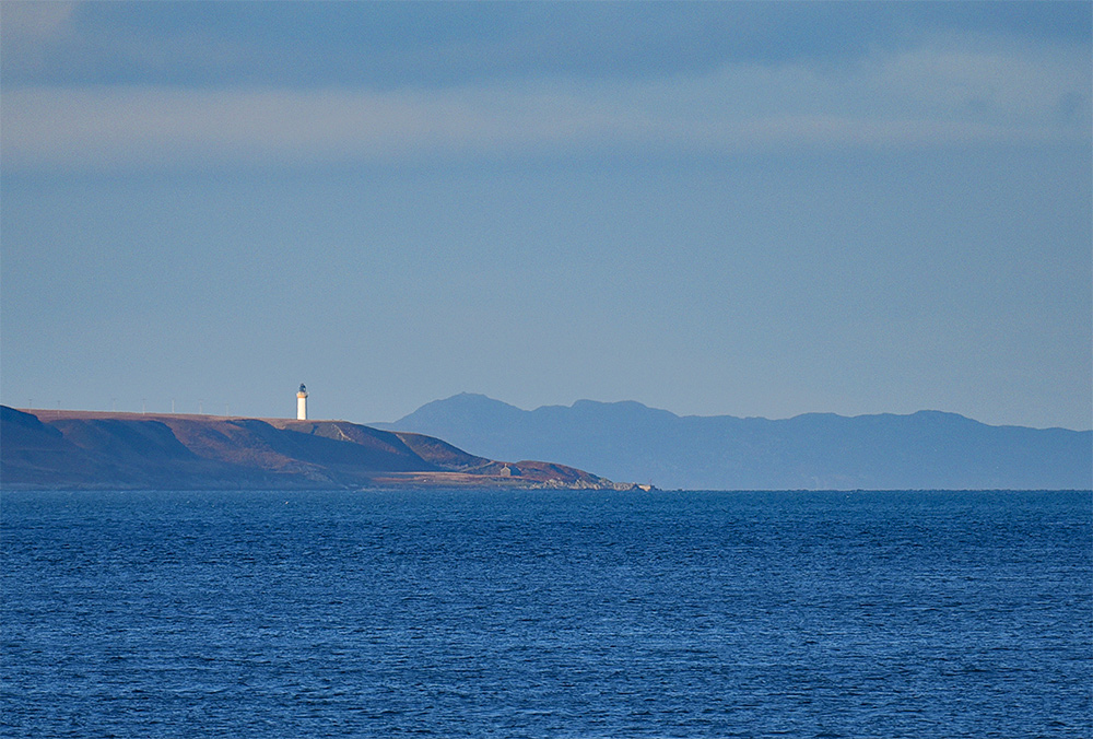 Picture of a lighthouse at the top of an island, another island in the background