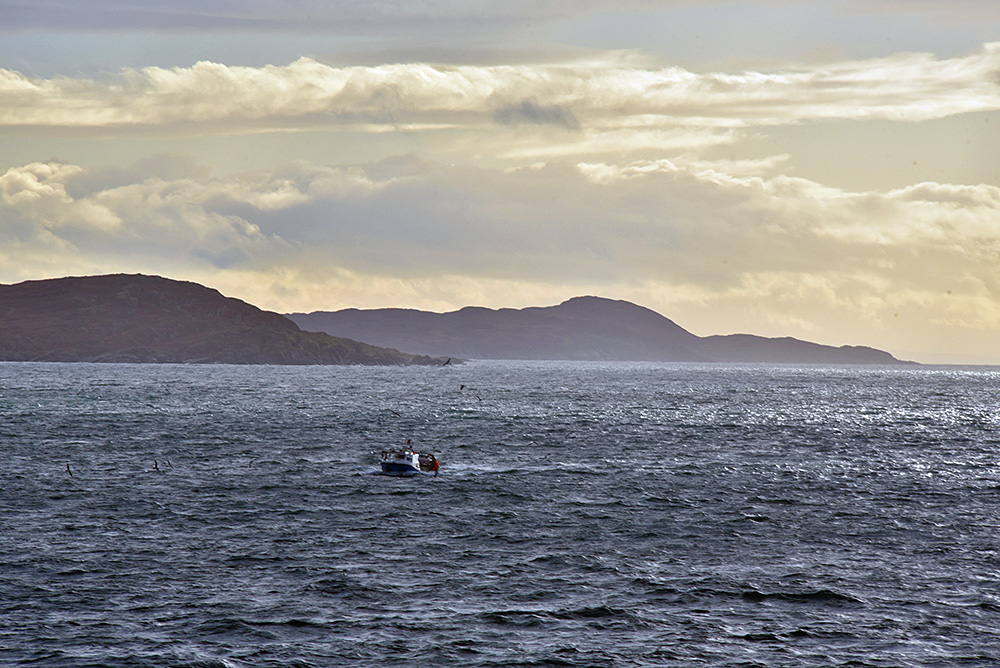 Picture of a small fishing boat off a small island, seen from a passing ferry