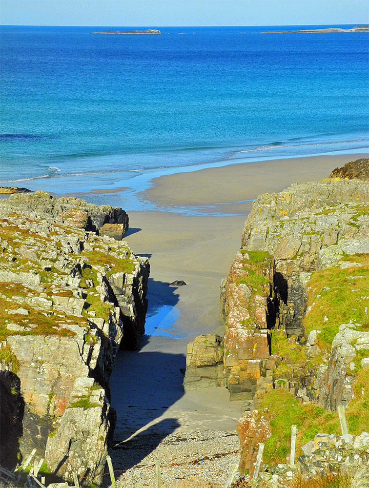 Picture of a gap between cliffs at the end of a sandy beach