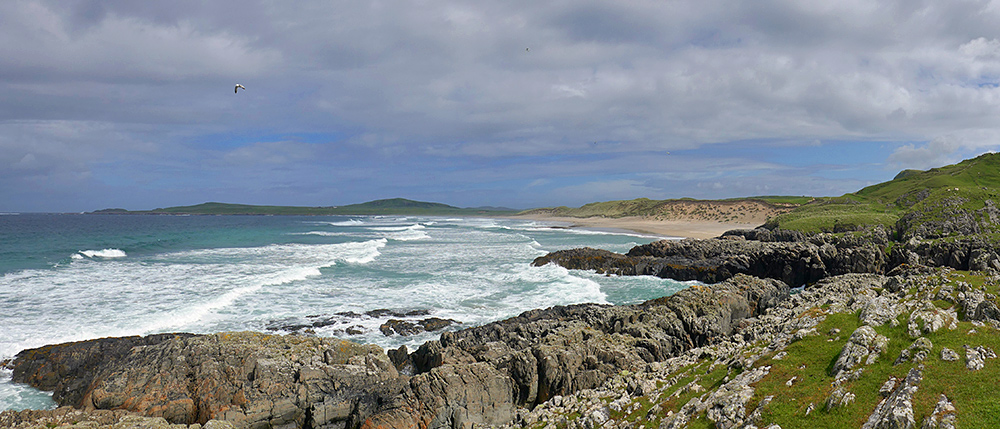 Panoramic picture of a bay with a beach seen from some low cliffs