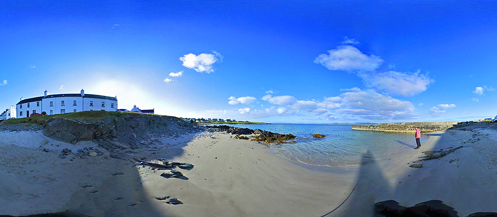 Panoramic picture of a small beach off a coastal village, a man standing on the beach