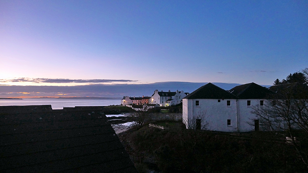 Picture of a dawn view over a coastal village, clear skies above, clouds in the distance