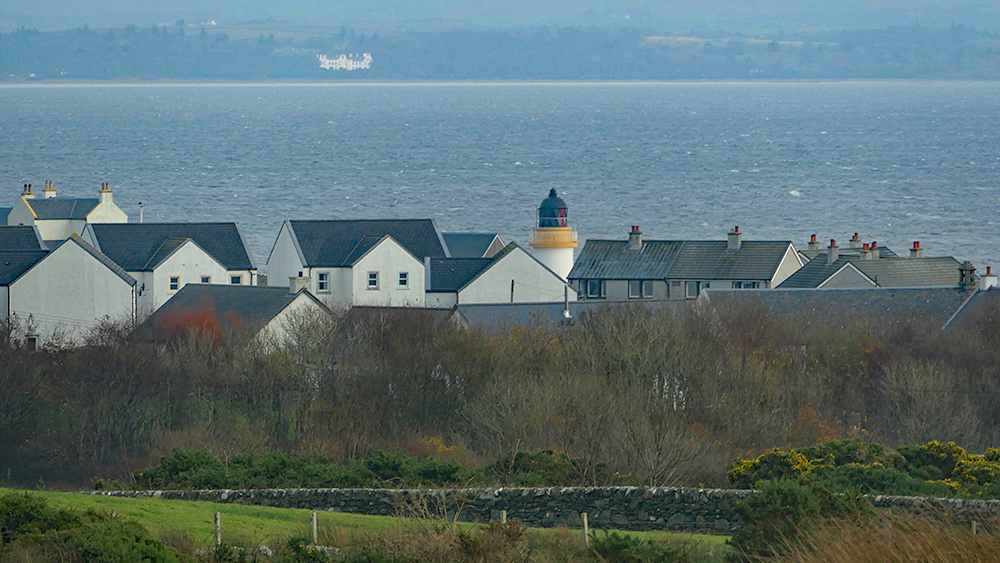 Picture of an old lighthouse behind mostly modern houses