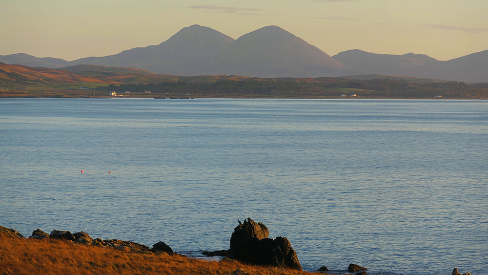 Picture of a view across a sea loch with a rocky shore to some distant mountains