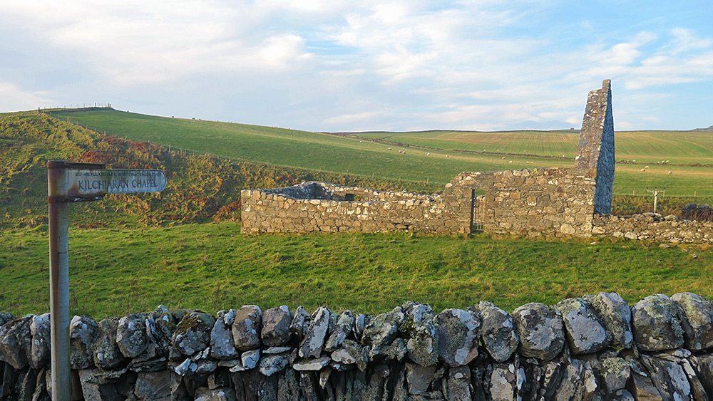 Picture of the ruin of a chapel in some nice mild November afternoon sunshine, a sign with its name in front of a wall in the foreground