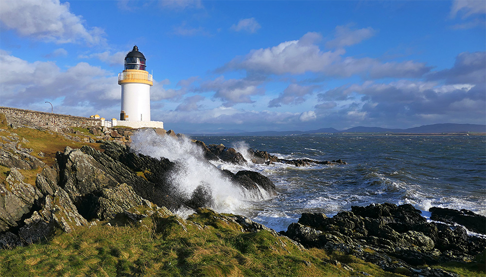 Picture of a small lighthouse with waves breaking over the rocks below