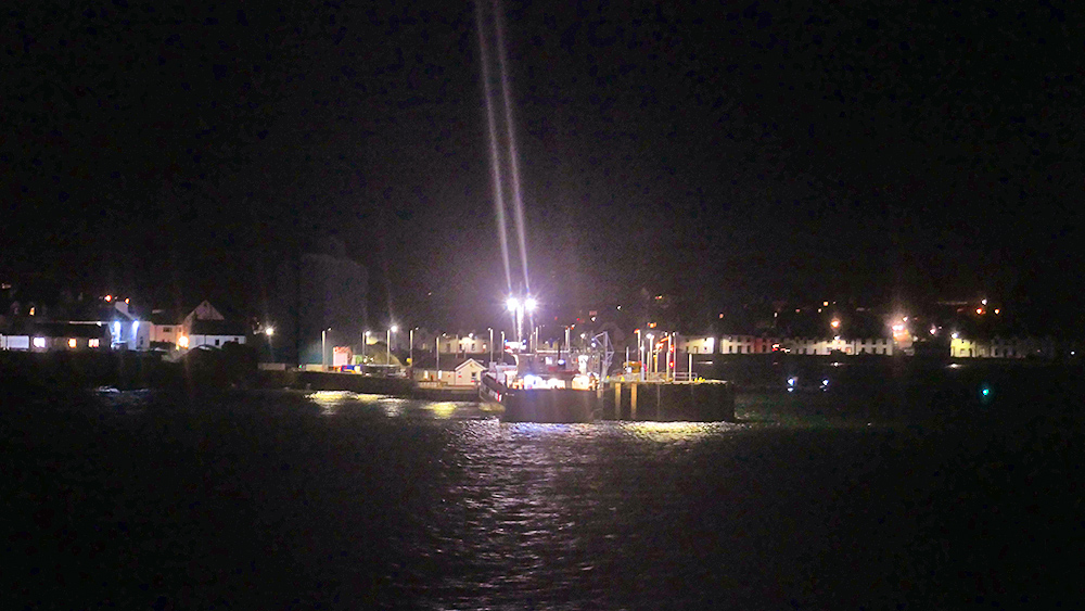 Picture of a small pier with a harbour at night, a cargo vessel berthed at the pier