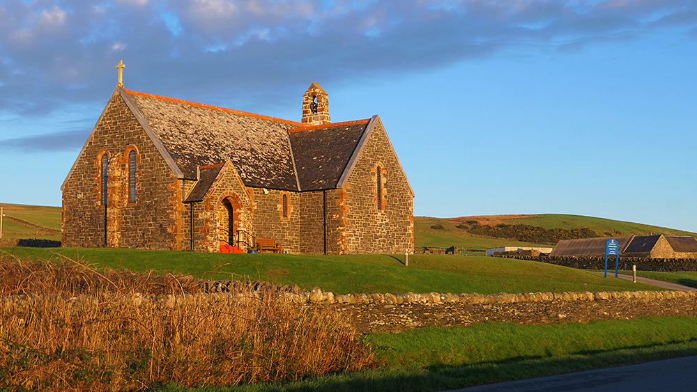 Picture of a church outside of a village in some mild dawn sunlight