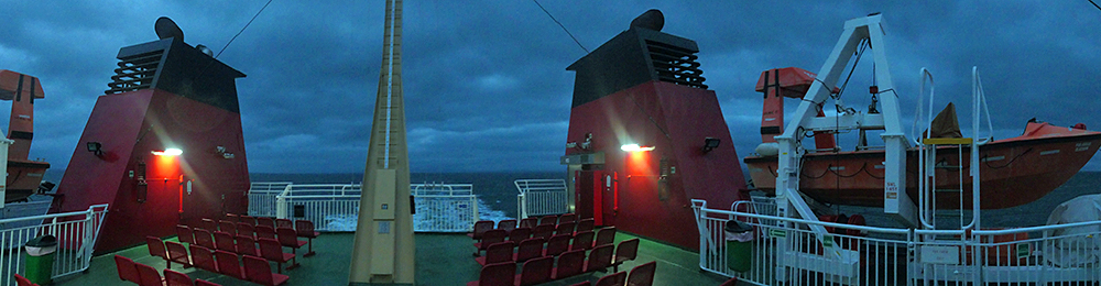 Panoramic picture of the top deck of a ferry under some dark clouds