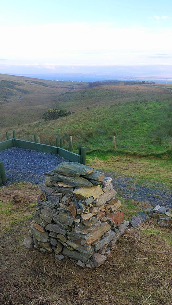 Picture of a memorial cairn above a glen (valley) leading to a sea loch