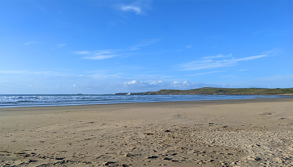 Picture of a view across a beach over a bay towards the end of the bay
