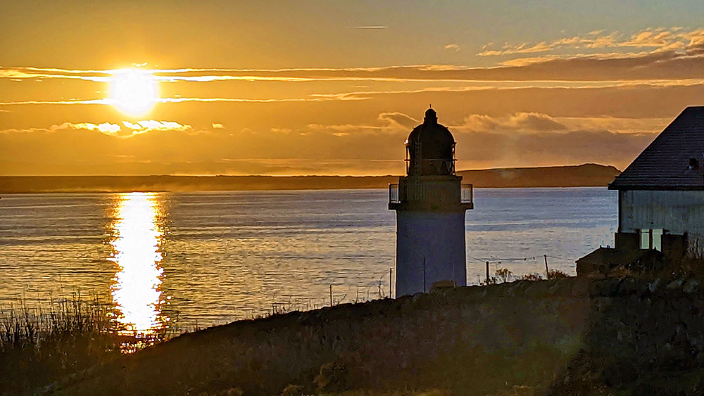 Picture of a November sunrise over a sea loch behind a lighthouse