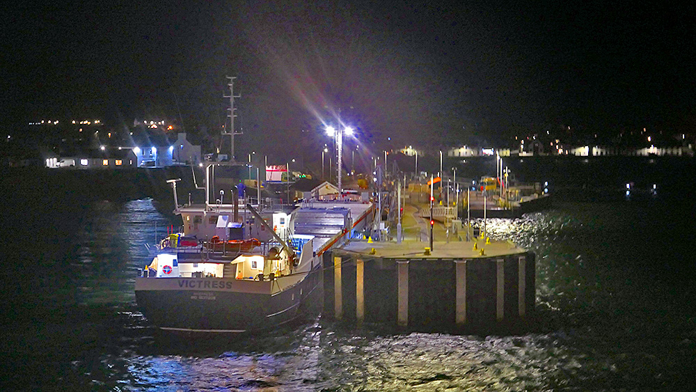 Picture of a small bulk carrier at the pier of a small harbour at night
