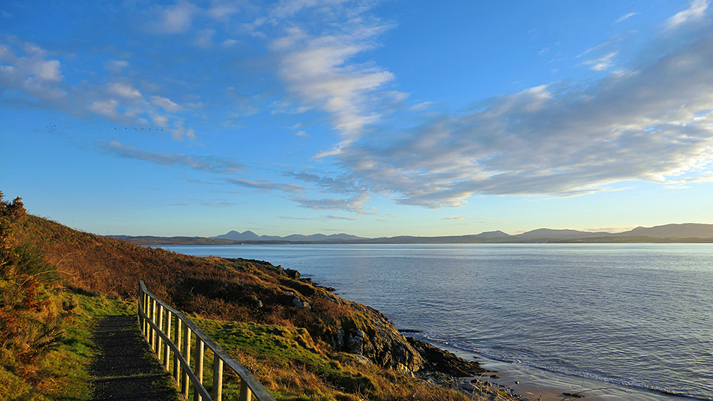 Picture of a view from a path down a shore to a beach at a sea loch