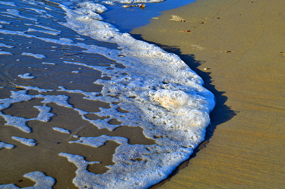 Picture of a wave running out on a beach with golden sand