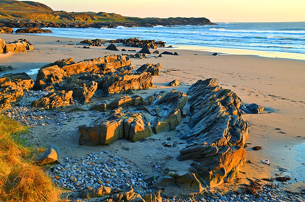 Picture of a beach with rocks and stones in the mild light not long before sunset