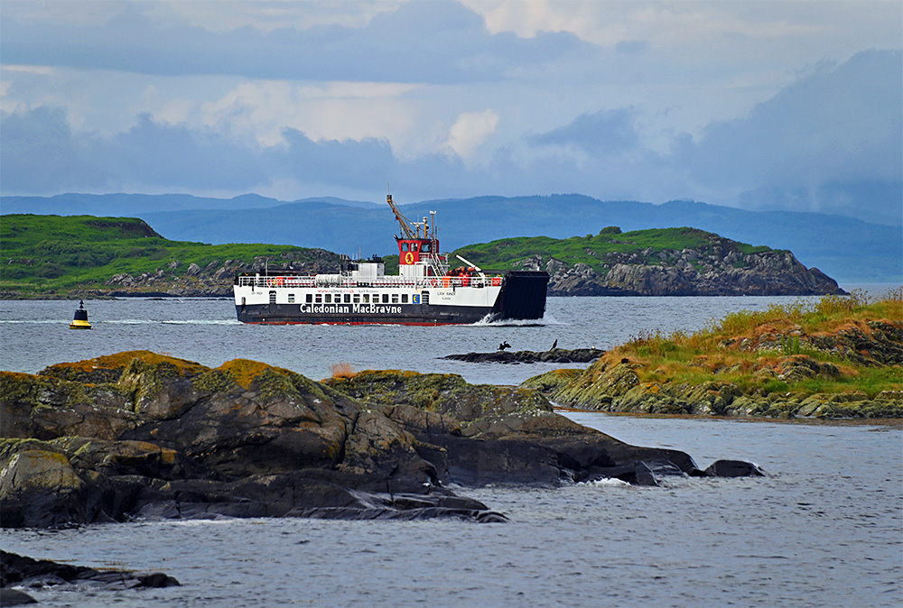 Picture of the Calmac ferry MV Loch Ranza cruising through a rocky coastal area with a buoy and birds on rocks