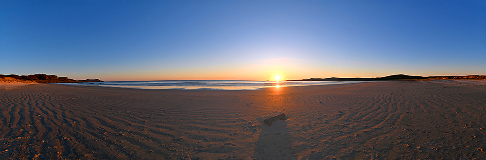 Panoramic picture of an April sunset at a wide sandy beach
