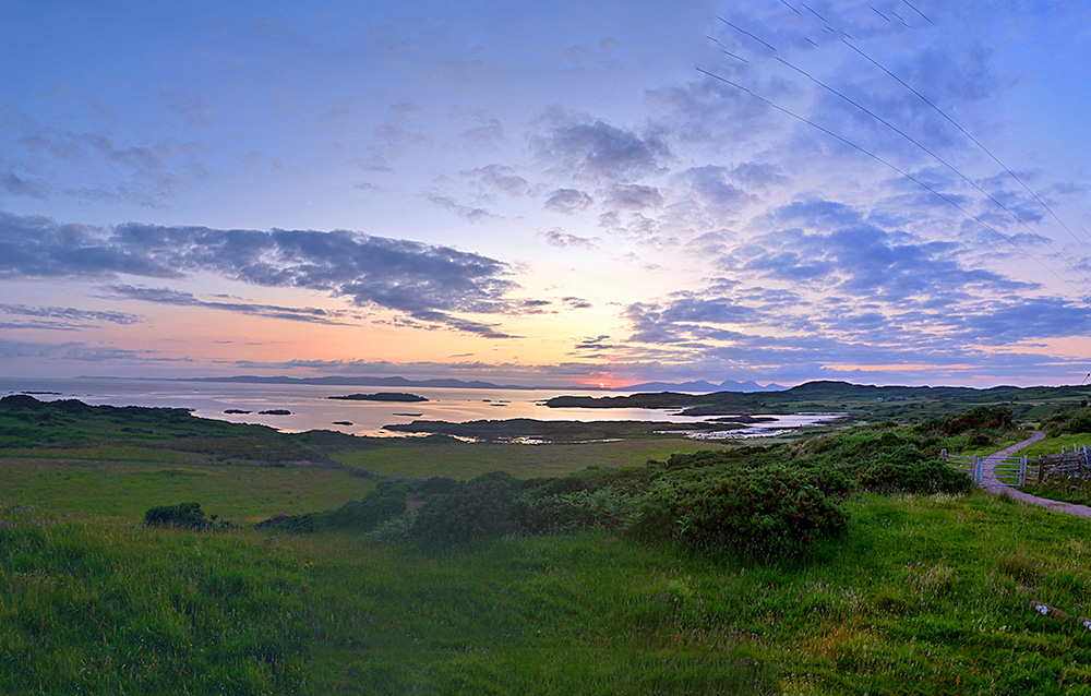 Panoramic picture of a sunset over two islands seen from a third island