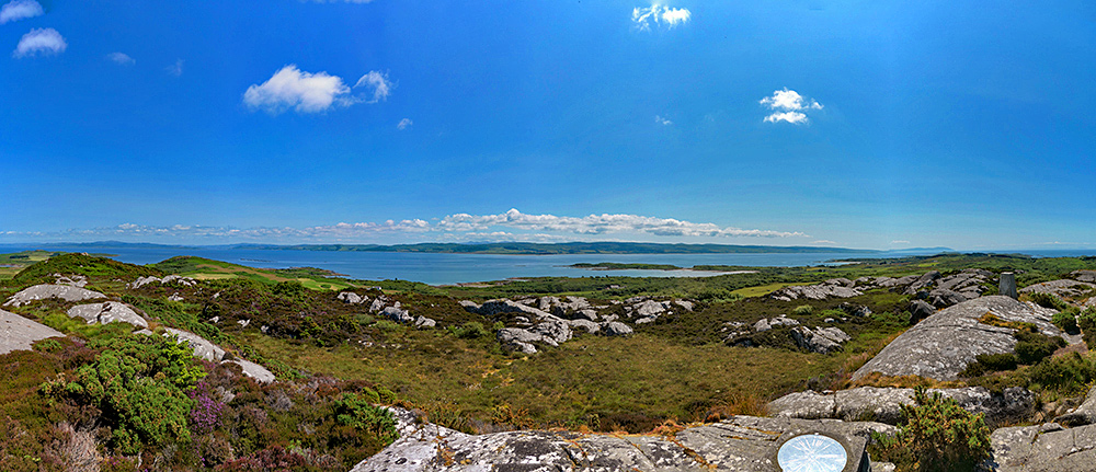 Panoramic picture of a view from a hill on an island looking over to a peninsula on the mainland on a bright sunny day