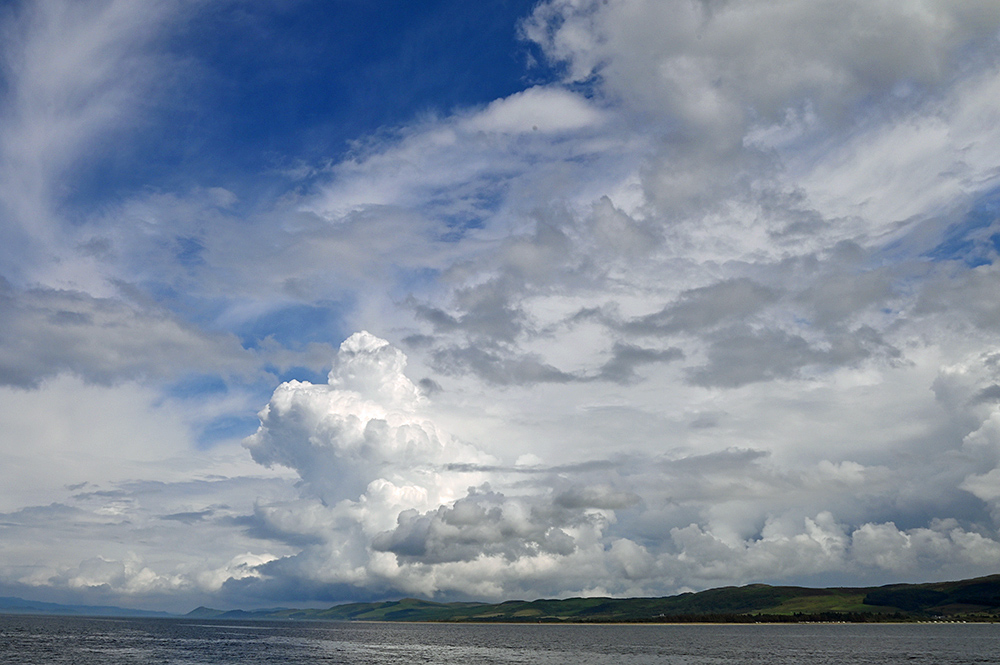 Picture of some dramatic big clouds over the mainland seen from a ferry to an island