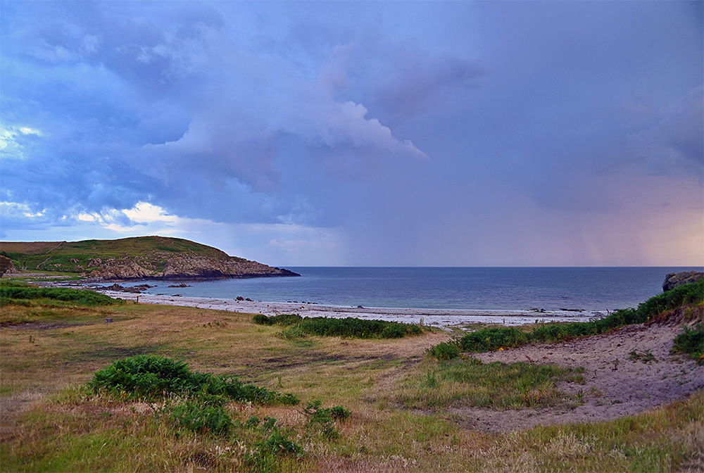 Picture of a beach under a cloudy sky with a rain shower approaching