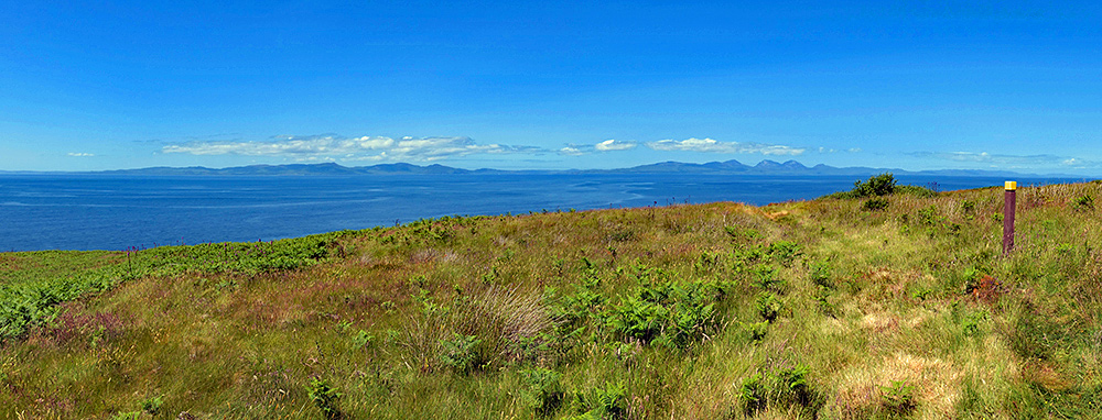 Panoramic picture of a view from rough path across the sea to two other islands