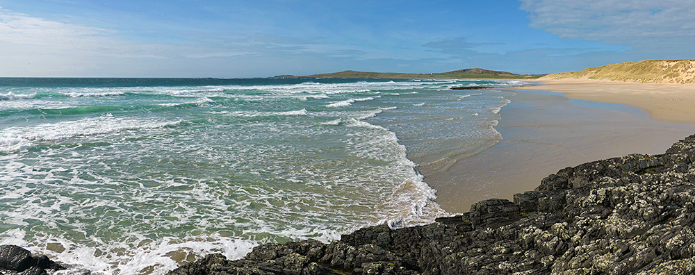 Panoramic picture of waves rolling on to a wide beach