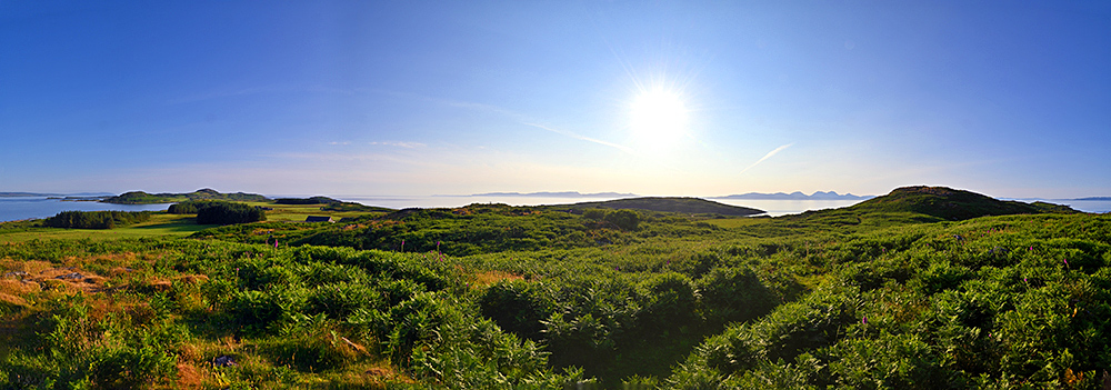 Panoramic picture of a view over an island with other islands visible on the horizon on a bright and sunny June evening